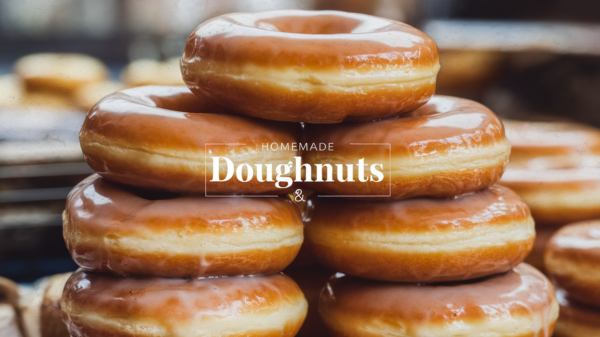 A plate of golden, fluffy homemade doughnuts coated in sugar glaze, with one doughnut topped with rainbow sprinkles, served on a rustic wooden table.